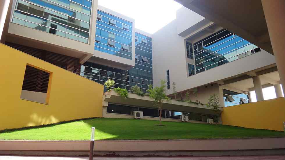 A view of Habib University’s main building with large glass windows and bright yellow walls, surrounded by well-maintained green lawns. The design showcases a contemporary style with multiple levels and large overhanging structures.