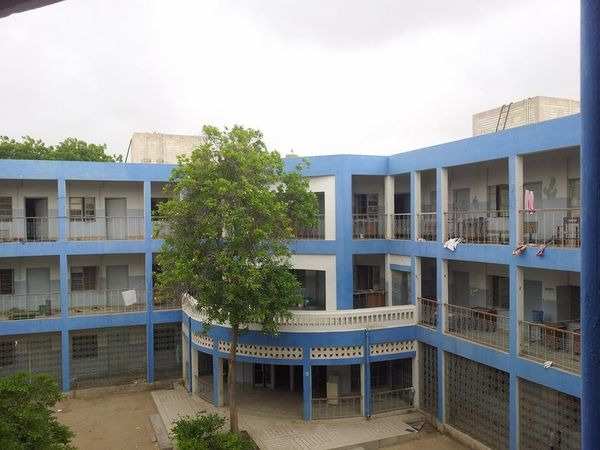 A three-story hostel building at NED University with blue and white walls, open corridors, and a central courtyard featuring a tree, offering a serene and comfortable living environment for students.